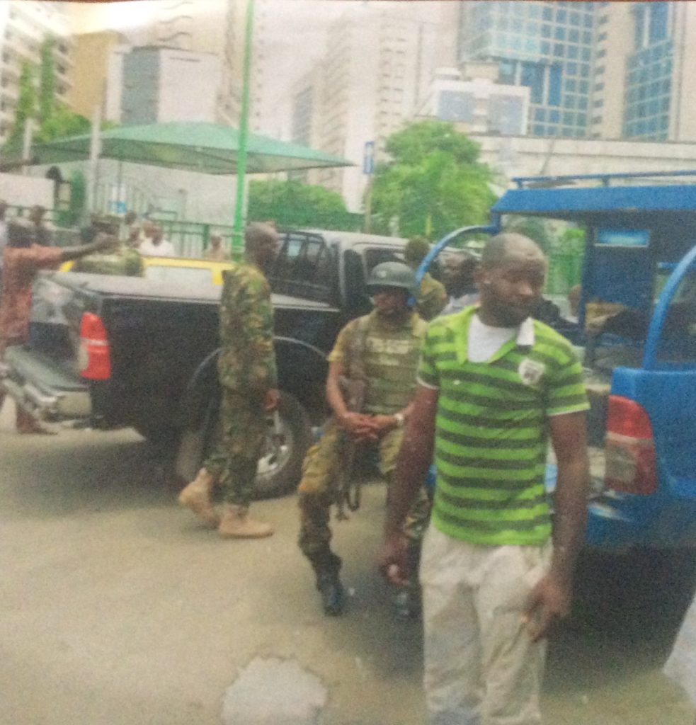 One of the earlier attempts at demolishing the building was captured by a passerby. The soldiers seen here had come to protect those intending to demolish the building. They were repelled in the end by a crowd of concerned residents led by Eric Awóbuyìdé and eventually the Nigerian Police. Photo source: Eric Awóbuyìdé.